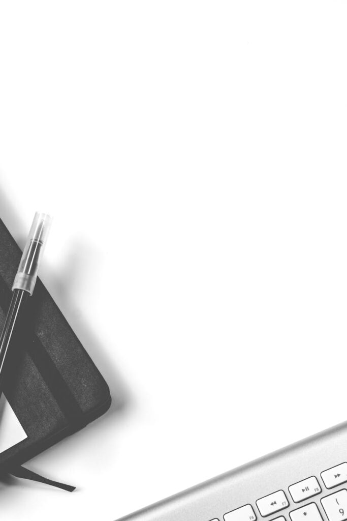 Minimalist flat lay of an office desk with notebook, keyboard, and smartphone.